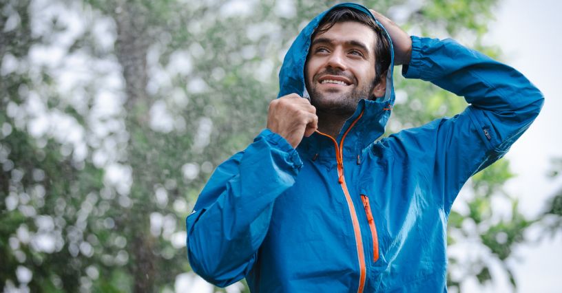Mężczyzna zakładający kaptur od kurtki przeciwdeszczowej w czasie deszczu