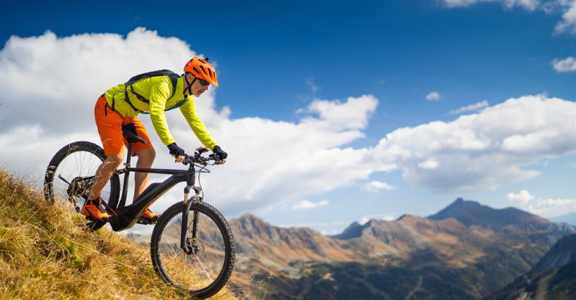 Mężczyzna w kasku i rowerowej odzieży zjeżdża z górki na rowerze MTB