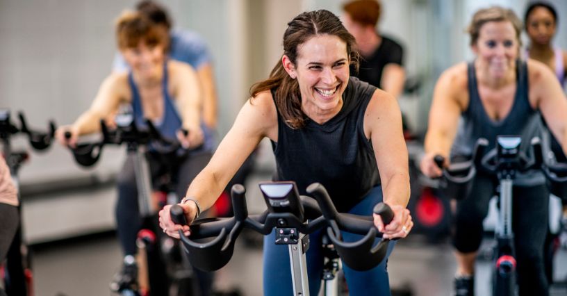 Kobiety ćwiczą na rowerach spinningowych w sali rowerowej na siłowni