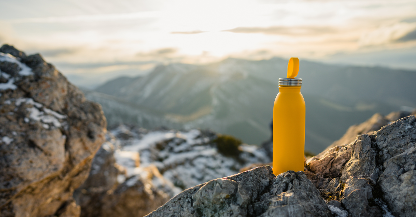 Żółta butelka termiczna stoi na górskiej skale