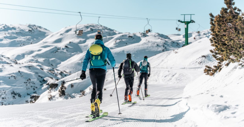 Trzech osoby na nartach biegowych i z kijkami biegną po przygotowanej trasie