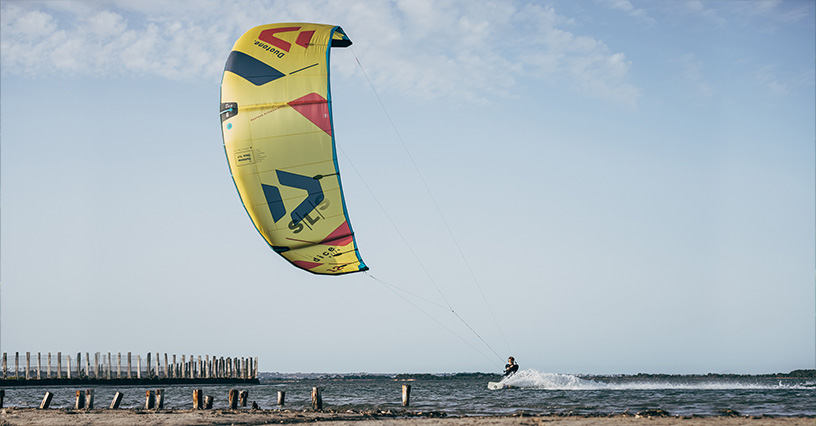 Osoba uprawiająca kitesurfing na otwartym morzu pod błękitnym niebem