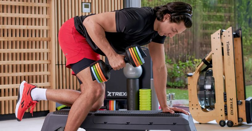 Mężczyzna ćwiczy triceps z hantlem w podporze na ławeczce prostej