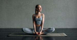 Kobieta w stroju do jogi siedząca na macie w pozycji motyla