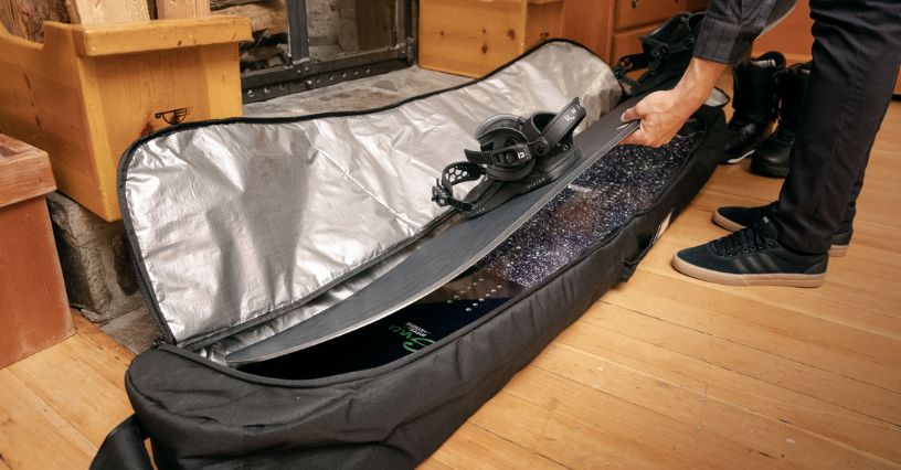 Mężczyzna wkładający deskę snowboardową do pokrowca