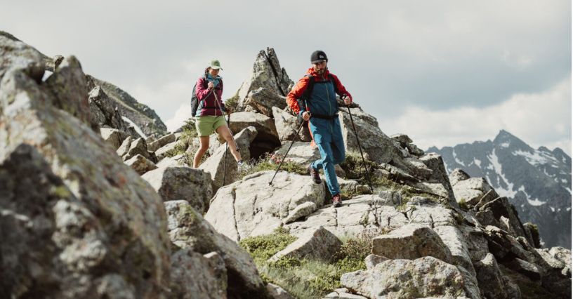 Para turystów z kijkami trekkingowymi szybko schodząca z kamienistej góry