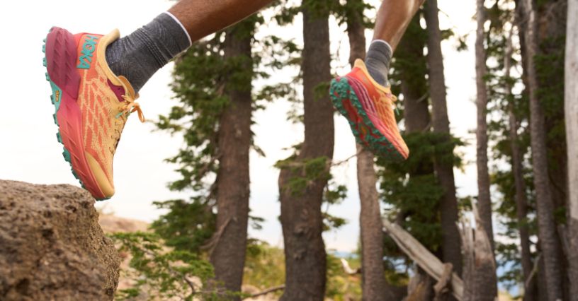 Biegacz trailowy biegnący przez las w butach Hoka