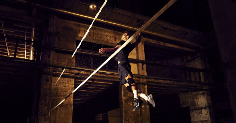 Siatkarz atakujący piłkę nad siatką