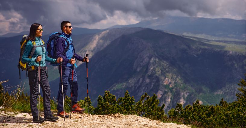 Para turystów z kijkami trekkingowymi w czasie wędrówki po górach
