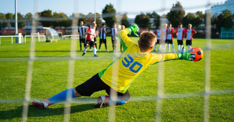 Młody bramkarz broniący piłkę po rzucie karnym