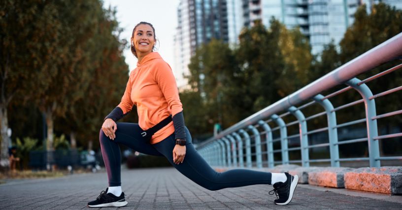 Kobieta z pasem biegowym w wykroku podczas rozgrzewki nóg przed biegiem