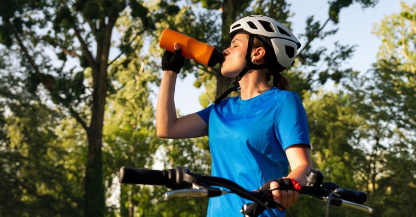 Rowerzystka pije izotonik podczas przerwy w jeździe po parku