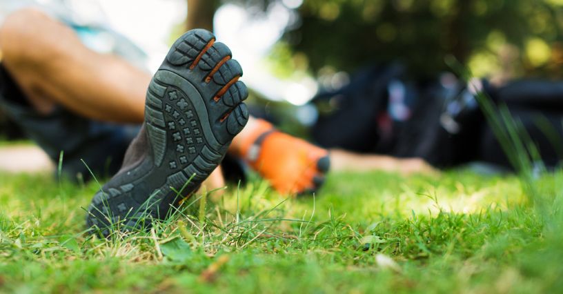 Męskie stopy w butach barefoot leżące na trawnie