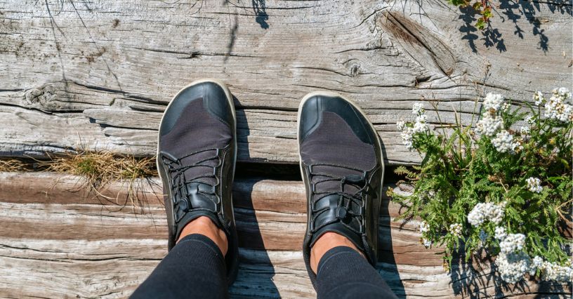 Kobiece stopy w butach barefoot na drewnianym pomoście podczas spaceru w wiosenny dzień