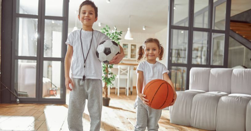Chłopiec z piłką do piłki nożnej i dziewczynka z piłką do koszykówki przygotowujący się na zajęcia sportowe