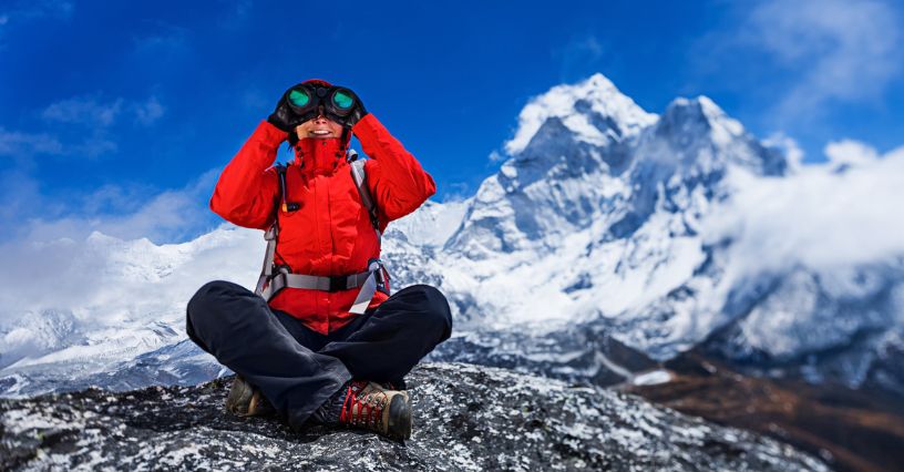 Kobieta obserwująca góry przez lornetkę