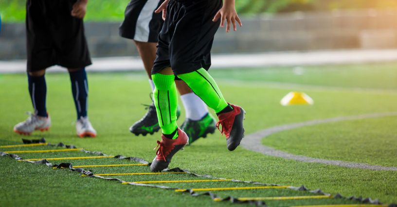 Piłkarz ćwiczący bieganie bokiem z drabinką koordynacyjną