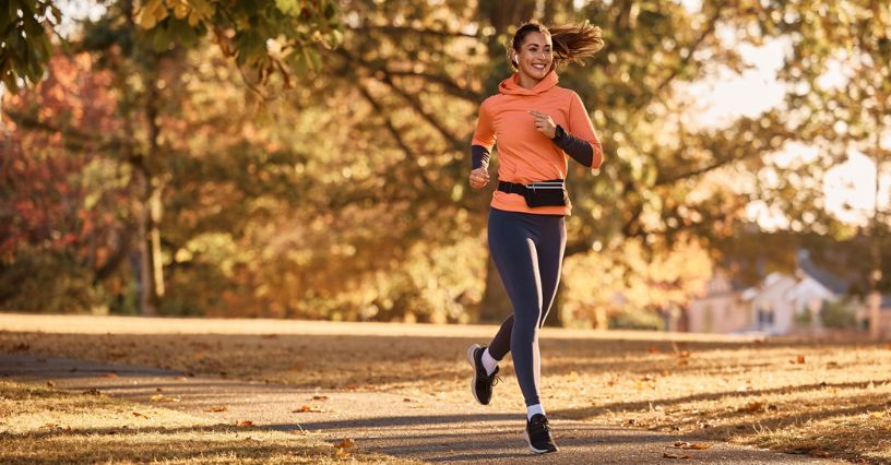 Kobieta w bluzie i legginsach do biegania biegająca po parku w jesienny dzień
