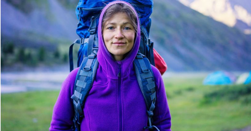 Dziewczyna w bluzie polarowej i z plecakiem w trakcie wyprawy górskiej