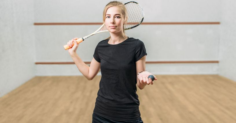 Dziewczyna trzymająca piłeczkę i rakietę do squasha