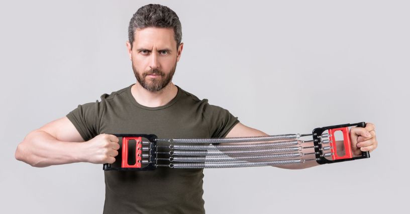 Mężczyzna rozciągający metalowy ekspander do ćwiczeń