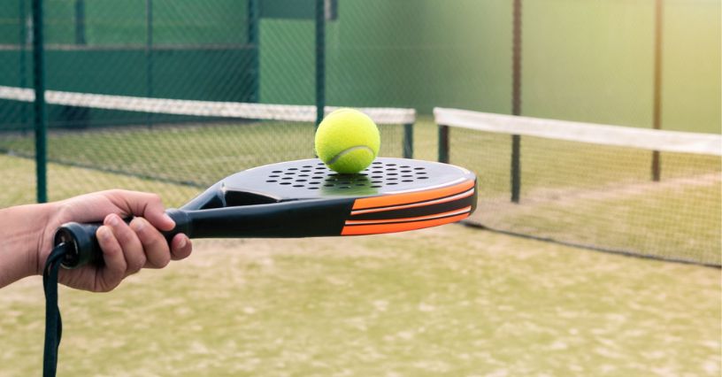 Człowiek trzymający rakietę do padla z ułożoną na niej piłką