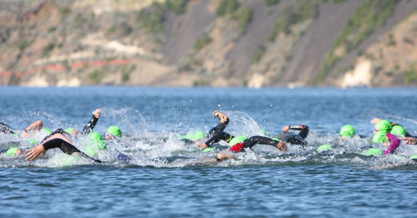 Zawodnicy pływają w zawodach triathlonowych na otwartym akwenie