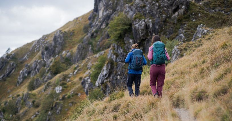 Dwie osoby w odzieży turystycznej i z plecakami wędrują górskim szlakiem