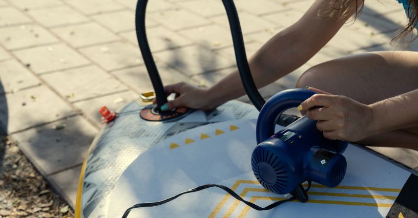 Kobieta używa elektrycznej pompki do pompowania deski SUP