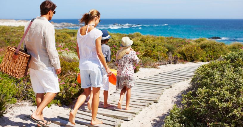 Rodzina idzie drewnianą ścieżką na plażę
