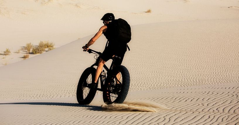 Mężczyzna jedzie na elektrycznym rowerze fatbike po piaszczystym terenie