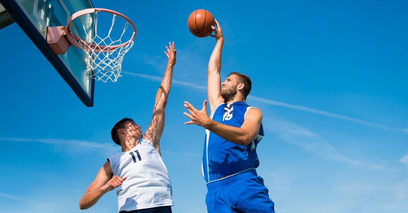 Koszykarze w dynamicznej akcji podczas meczu 3x3 na tle błękitnego nieba