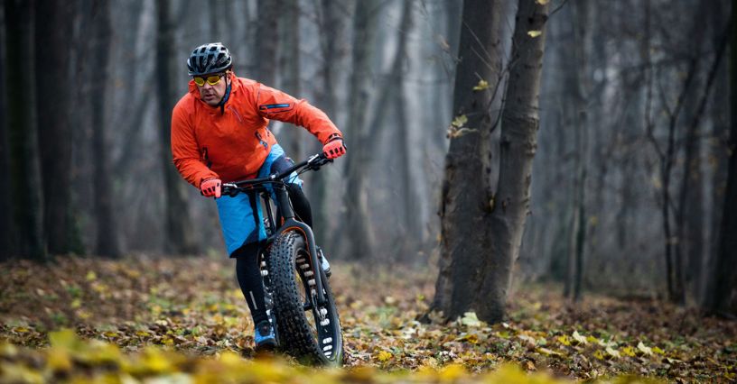 Mężczyzna na fatbike'u jeździ po leśnej ścieżce