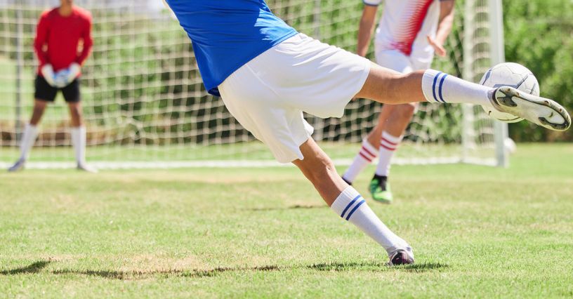 Piłkarz w korkach piłkarskich oddaje strzał na bramkę podczas meczu