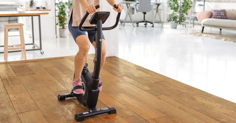 Kobieta trenuje na rowerze stacjonarnym w domowym wnętrzu