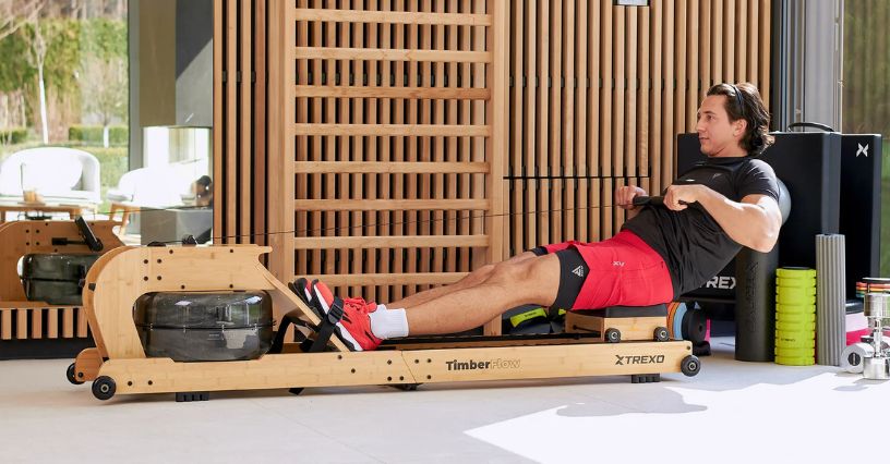 Mężczyzna ćwiczy na wodnym ergometrze wioślarskim w domowej siłowni