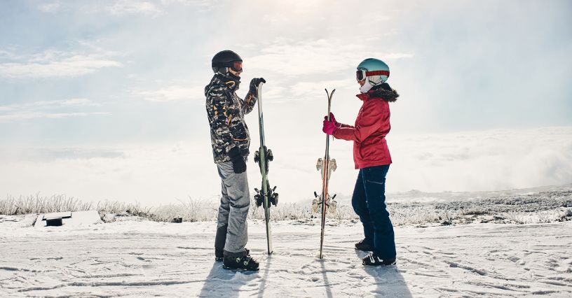 Para narciarzy stojąca na szczycie stoku podczas przerwy w jeździe na nartach