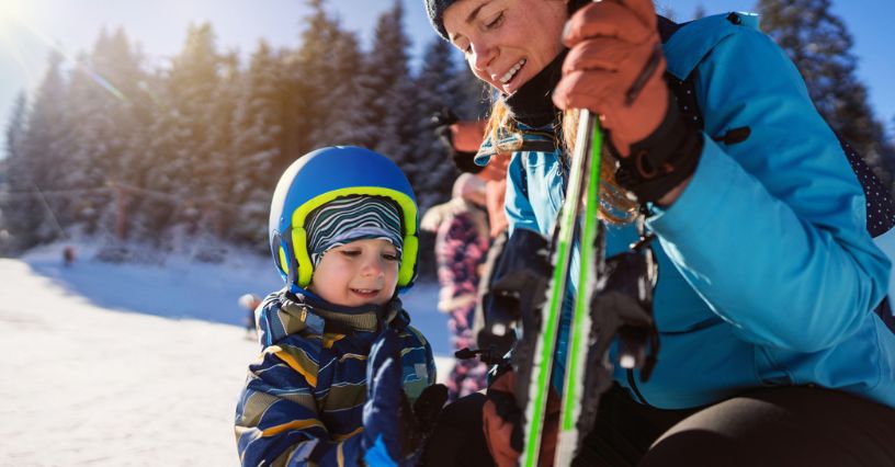 Narciarka z dzieckiem przygotowują się do jazdy na nartach