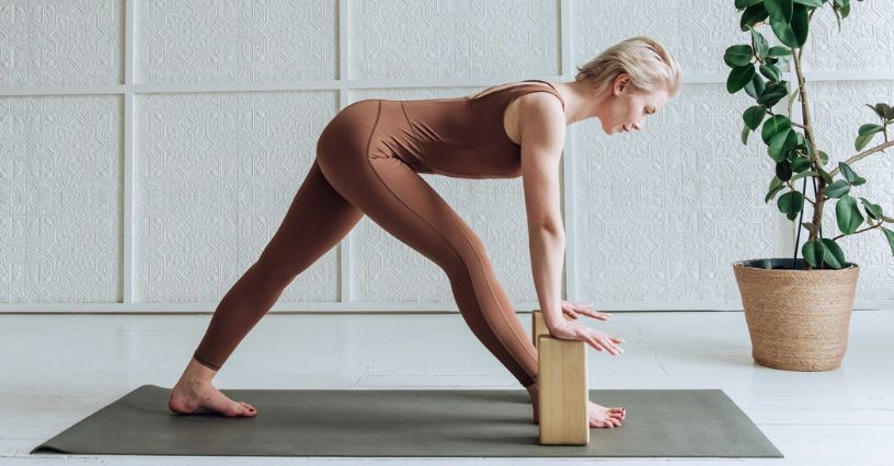 Kobieta wykonuje pozycje jogi z użyciem drewnianych kostek na macie