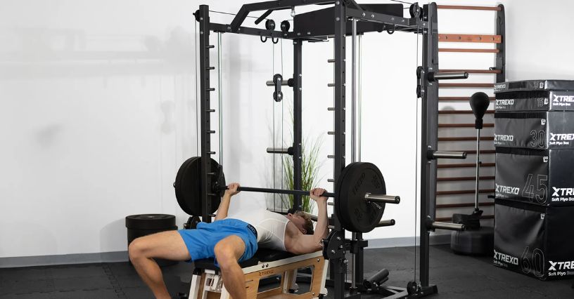 Mężczyzna ćwiczy wyciskanie sztangi na atlasie w domowej siłowni