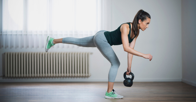 Kobieta ćwiczy martwy ciąg jednonóż z kettlebell w domu