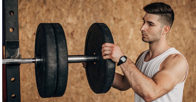 Mężczyzna zakłada obciążenie bitumiczne na sztangę