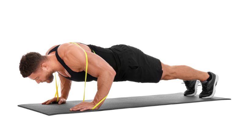 Mężczyzna wykonuje pompki z gumą powerband na plecach