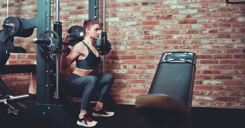 Kobieta korzysta z suwnicy Smitha w siłowni