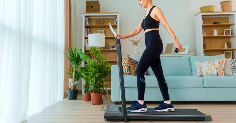 Kobieta w stroju sportowym chodzi po bieżni w domu