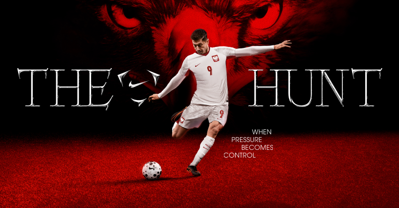 Robert Lewandowski w stroju domowym reprezentacji Polski kopie piłkę na czerwonym tle z napisem The Hunt