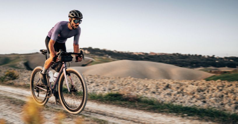 Mężczyzna w kasku jedzie na rowerze graelowym szutrowa drogą