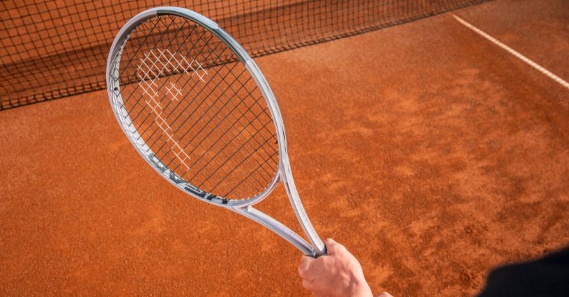 Tenisista trzyma rakietę HEAD Squared podczas gry na korcie ceglastym