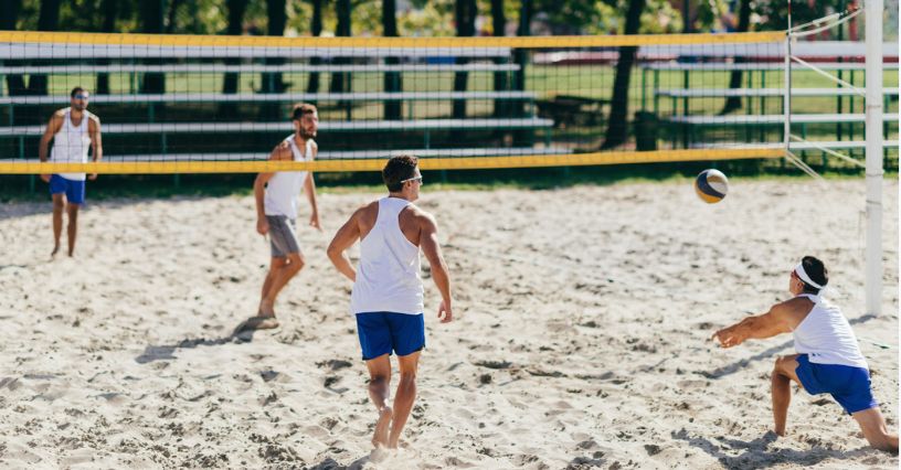 Czterech mężczyzn gra w siatkówkę plażową w słoneczny dzień