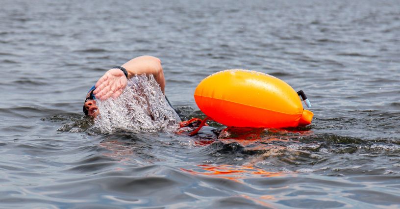 Pływak z bojką asekuracyjną podczas pływania open water